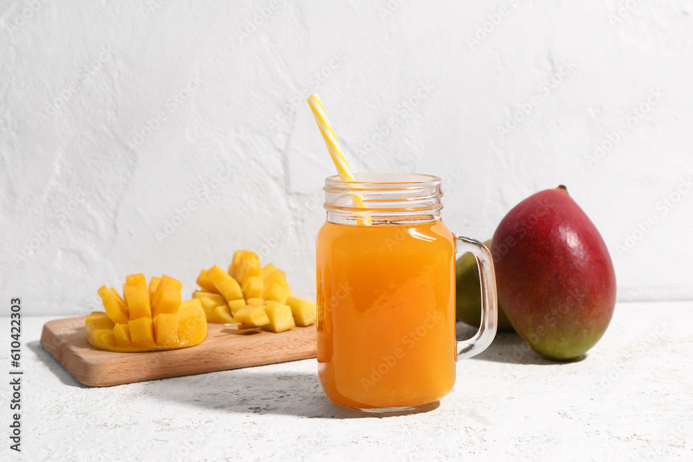 Mason jar of fresh mango smoothie on light background