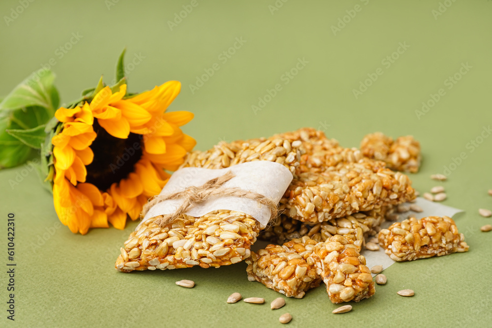 Sunflower with tasty kozinaki and seeds on green background