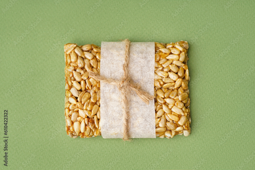 Tasty kozinaki in parchment on green background