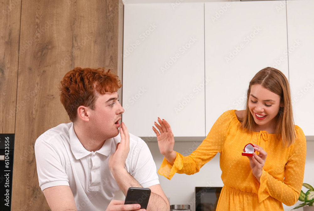 Young woman proposing to her boyfriend in kitchen