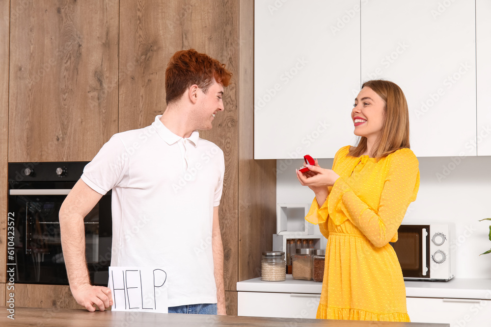 Young woman proposing to her boyfriend in kitchen