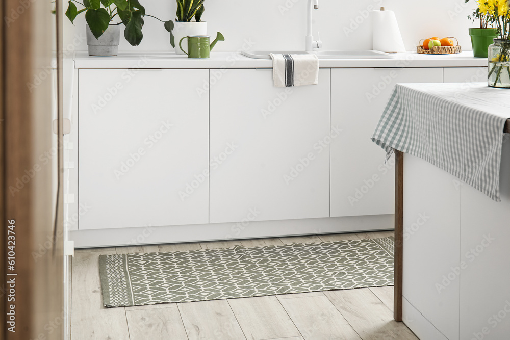 Stylish rug on floor in light kitchen