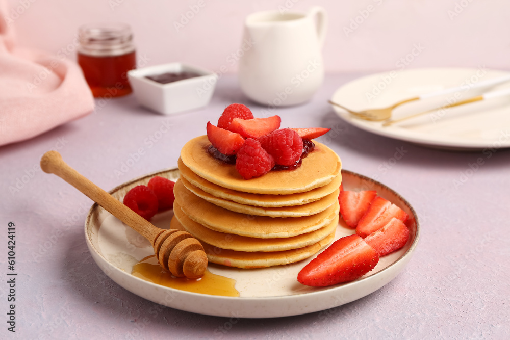 Plate with sweet pancakes, berries and honey on pink background, closeup