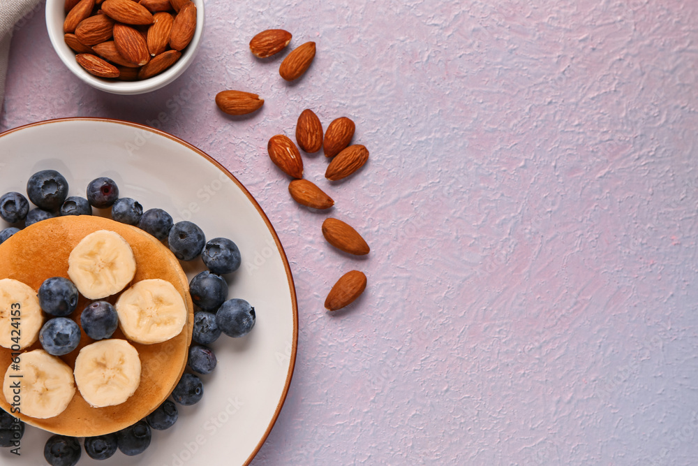 Plate with sweet pancakes, banana, blueberry and nuts on pink background