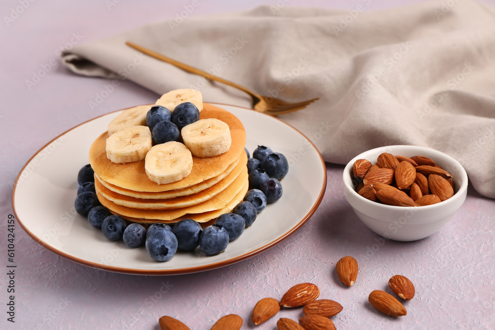 Plate with sweet pancakes, banana, blueberry and nuts on pink background, closeup