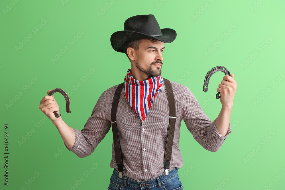 Handsome cowboy with horseshoes on green background