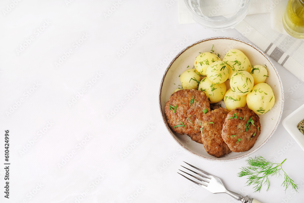 Bowl with cutlets, boiled baby potatoes and dill on white table in kitchen