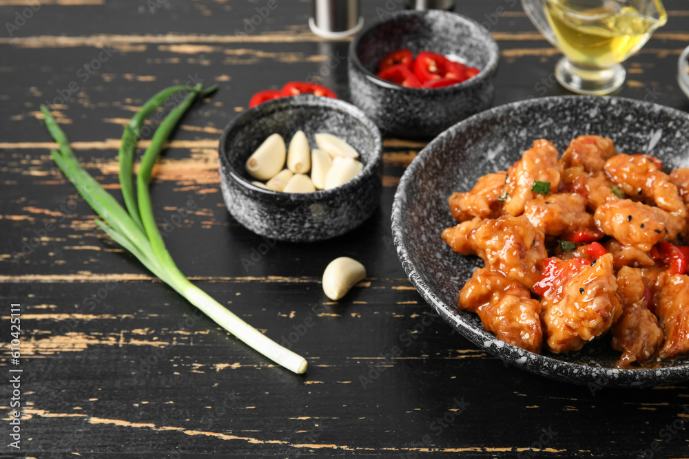 Tasty sweet and sour chicken in bowl with spices on dark wooden background, closeup