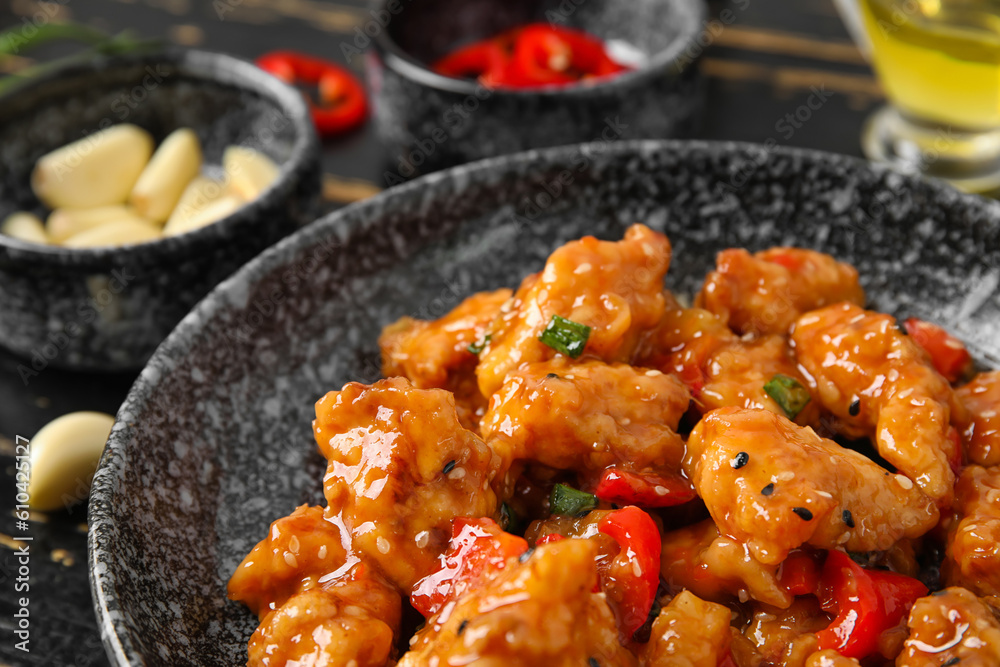 Bowl with tasty sweet and sour chicken on dark wooden background, closeup