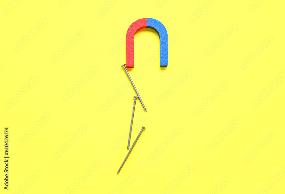 Magnet attracting nails on yellow background