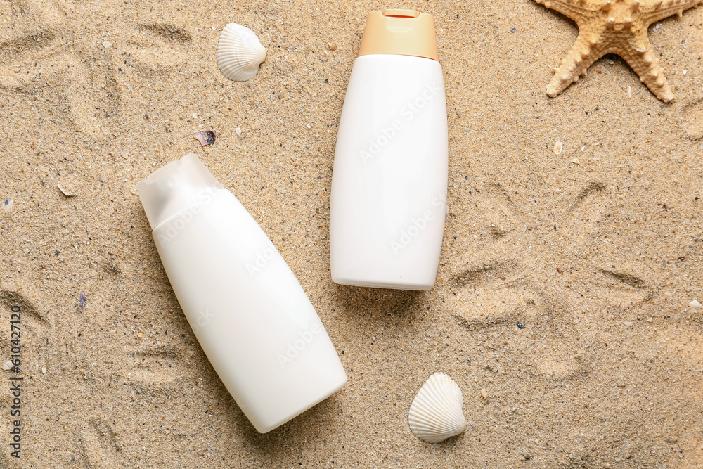 Creative composition with bottles of sunscreen cream, starfish and seashells on sand