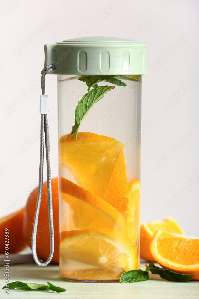 Sports bottle of infused water with orange slices on white background