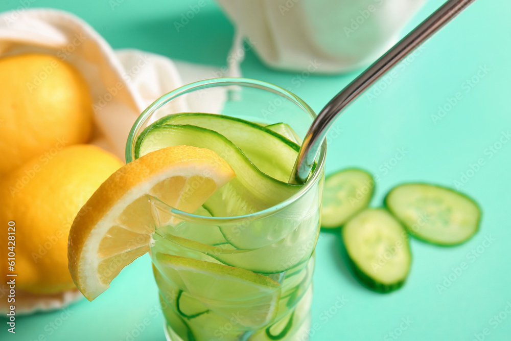 Glass of infused water with cucumber slices on turquoise background