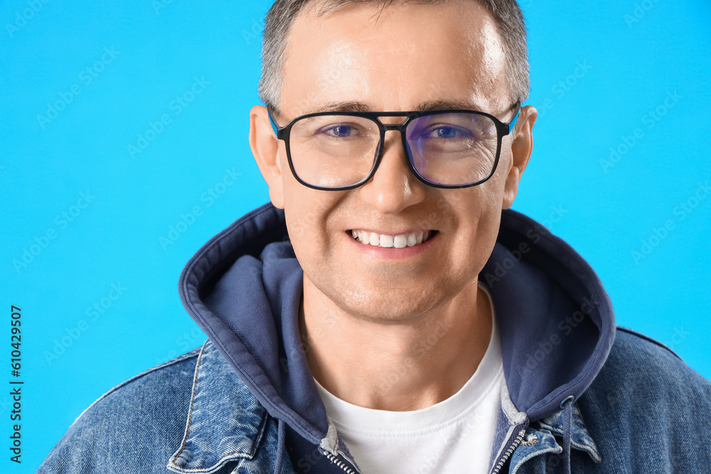 Mature man in eyeglasses on blue background, closeup