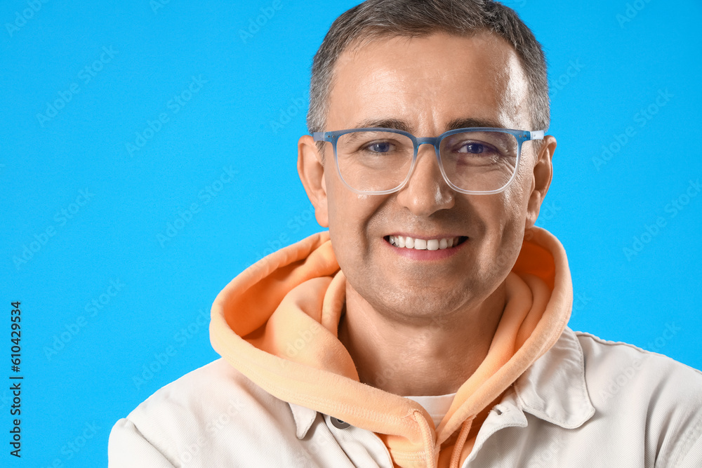 Mature man in eyeglasses on blue background, closeup