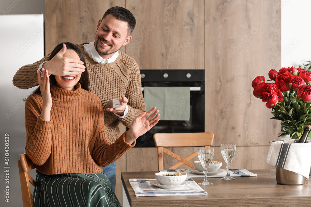 Young man proposing to his girlfriend in kitchen