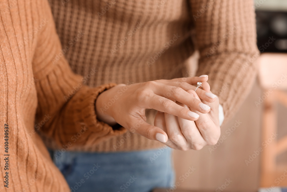 Young man putting engagement ring on his girlfriends finger in kitchen, closeup