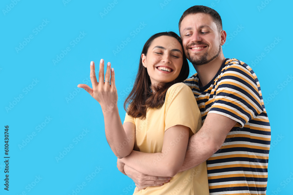 Happy engaged couple hugging on blue background