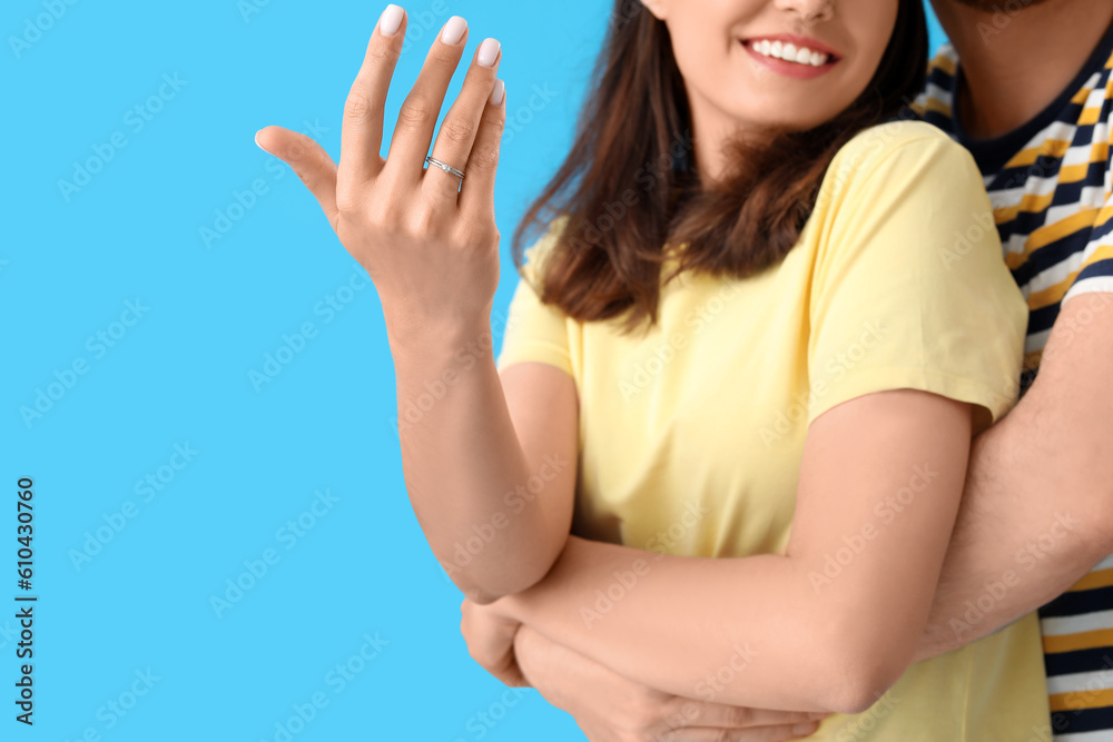 Happy engaged couple hugging on blue background, closeup