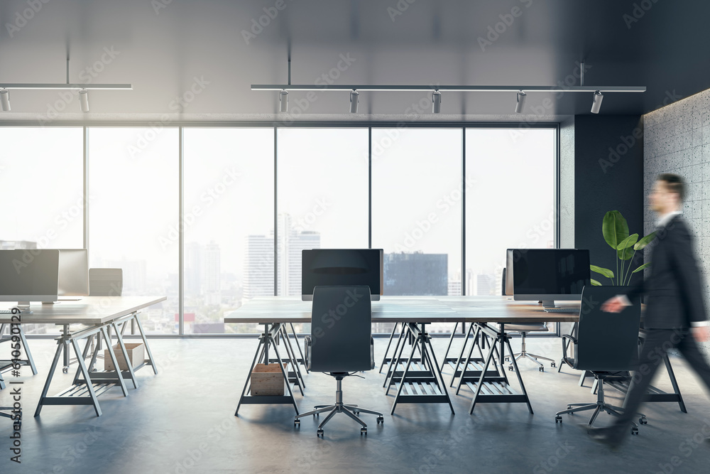 Blurry businessman walking in a modern open space office interior with big window with city view on 