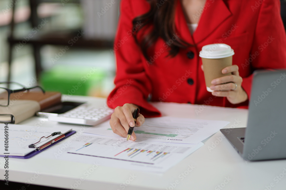 Businesswoman doing accounting work in the office analyzing charts in financial reports with a calcu