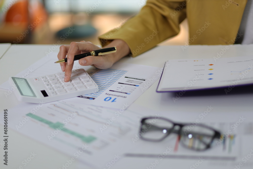 Businesswoman doing accounting work in the office analyzing charts in financial reports with a calcu