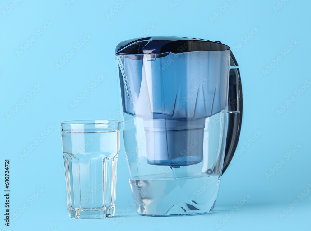 Water filter jug with glass on blue background