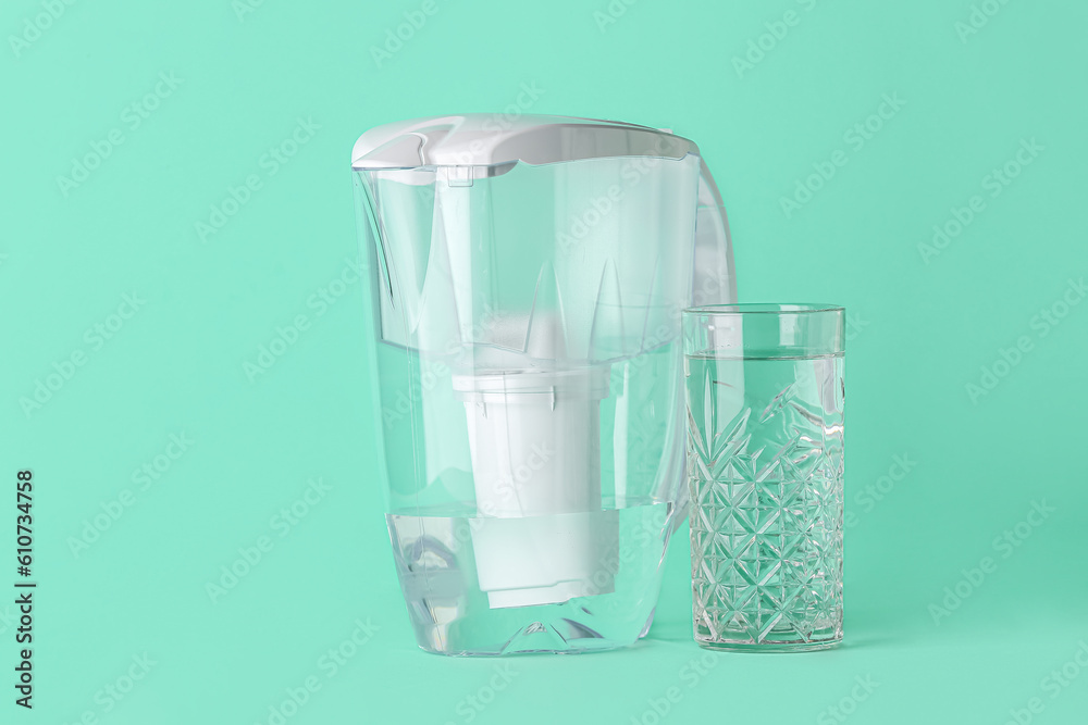 Water filter jug with glass on green background