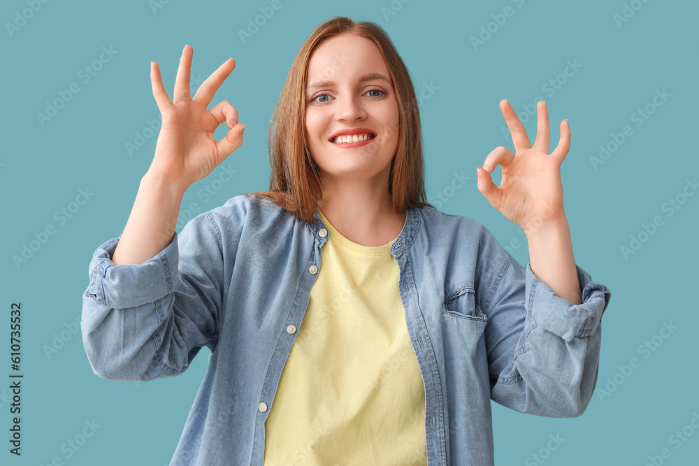 Beautiful redhead woman showing OK on blue background