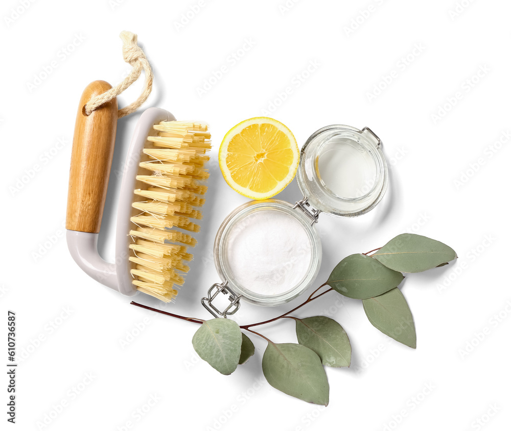 Jar of baking soda, cleaning brush, lemon and eucalyptus branch on white background