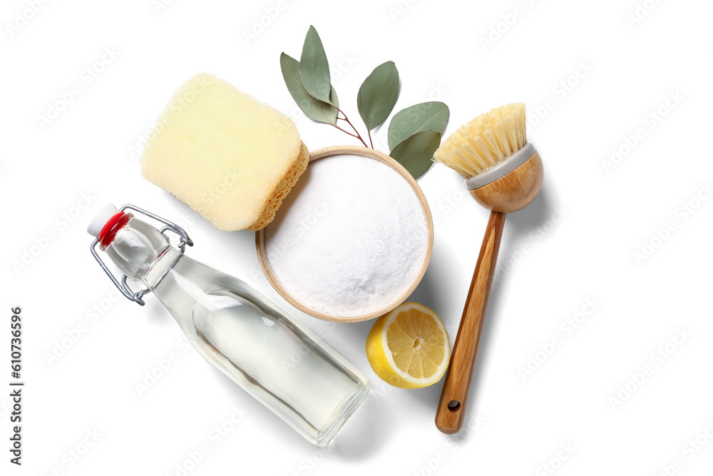 Bowl of baking soda, vinegar, cleaning brush, sponge and lemon on white background