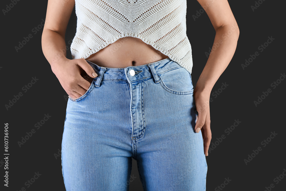 Young woman in stylish jeans on dark background, closeup