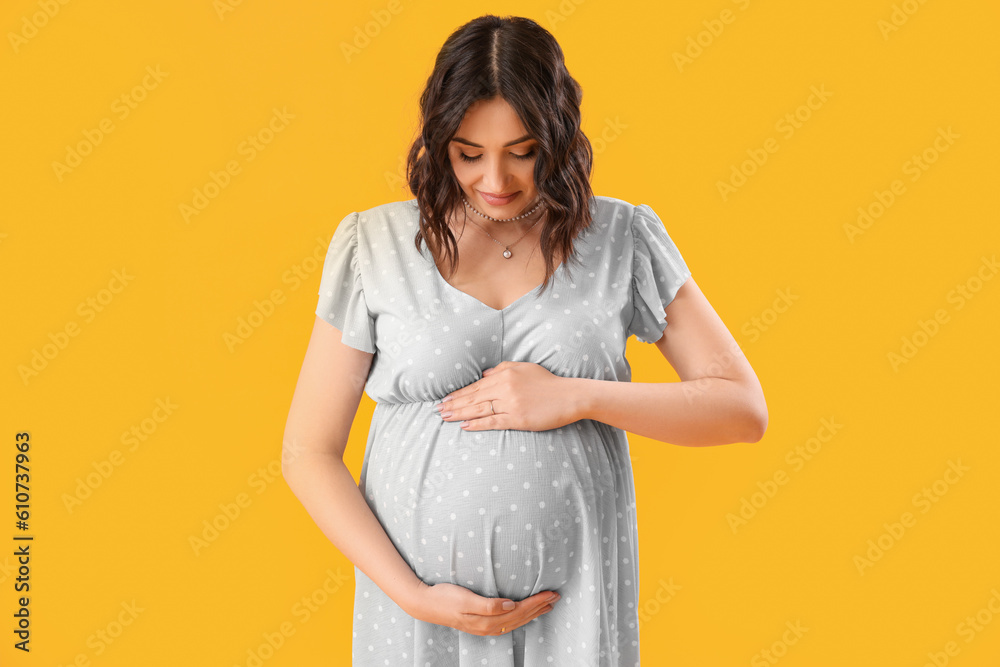 Young pregnant woman on yellow background