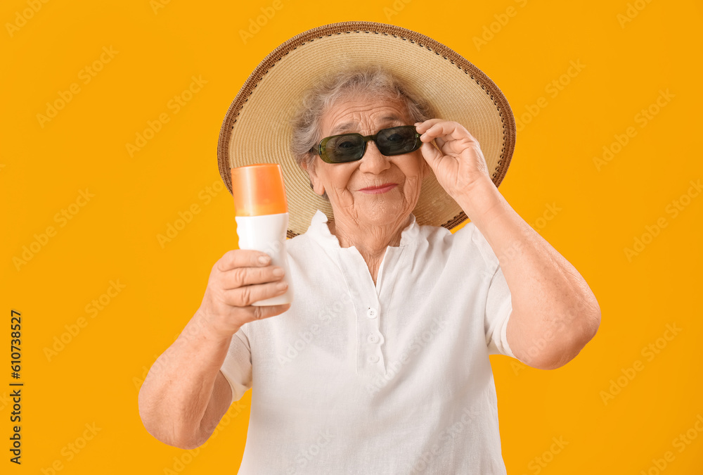 Senior woman with sunscreen cream on orange background