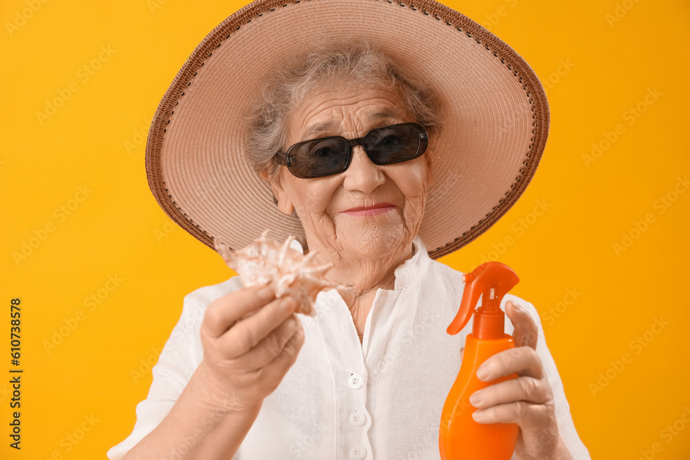 Senior woman with sunscreen cream and seashell on orange background, closeup