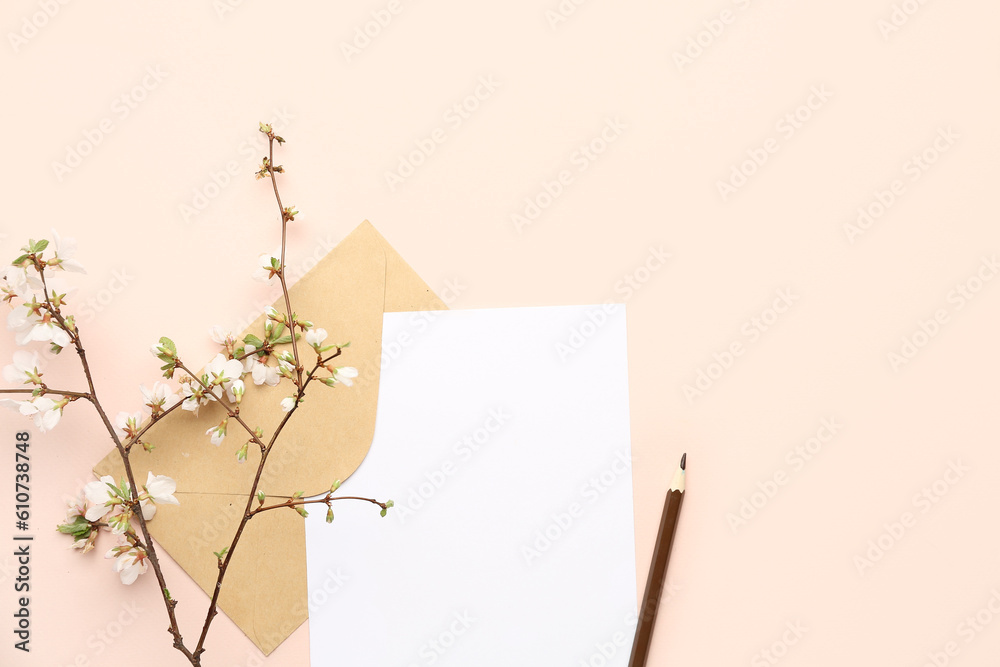 Blooming tree branch with white flowers, blank paper sheet, pencil and envelope on beige background