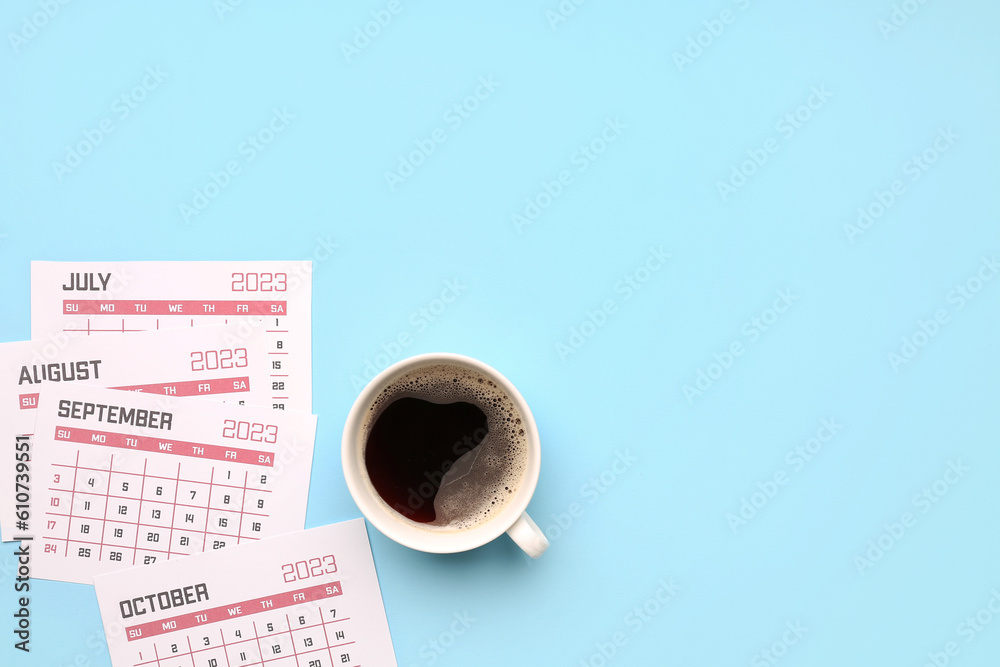 Pages of calendar and cup of coffee on blue background