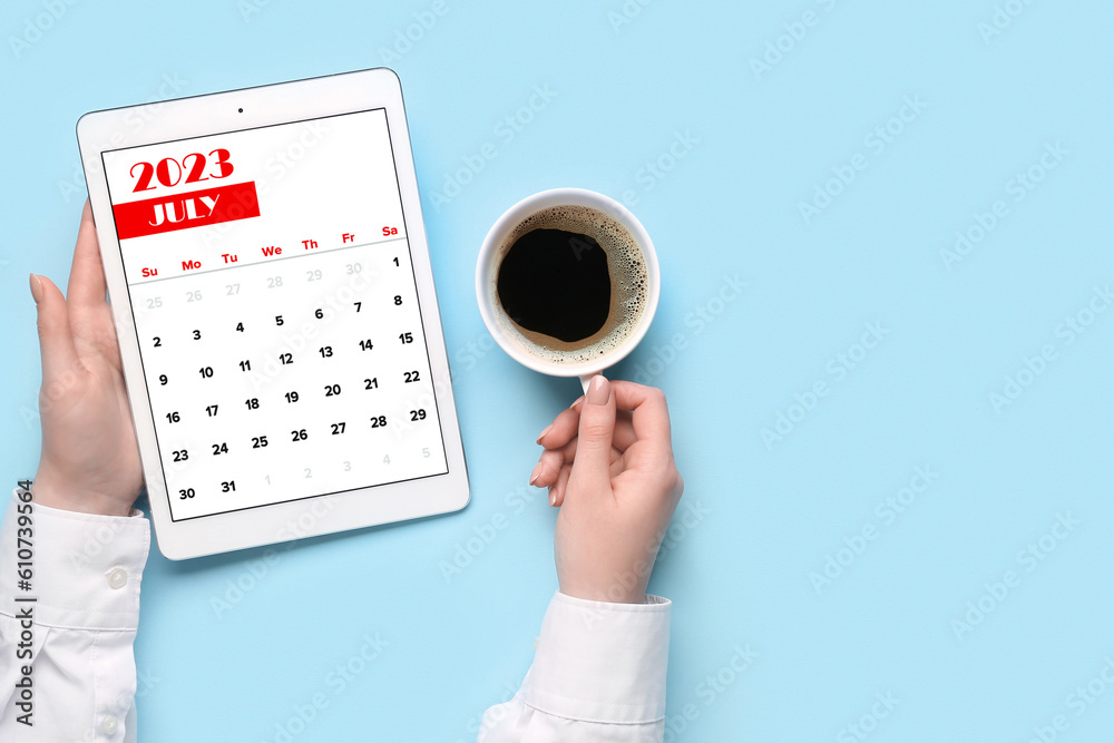 Woman holding tablet computer with calendar and cup of coffee on blue background