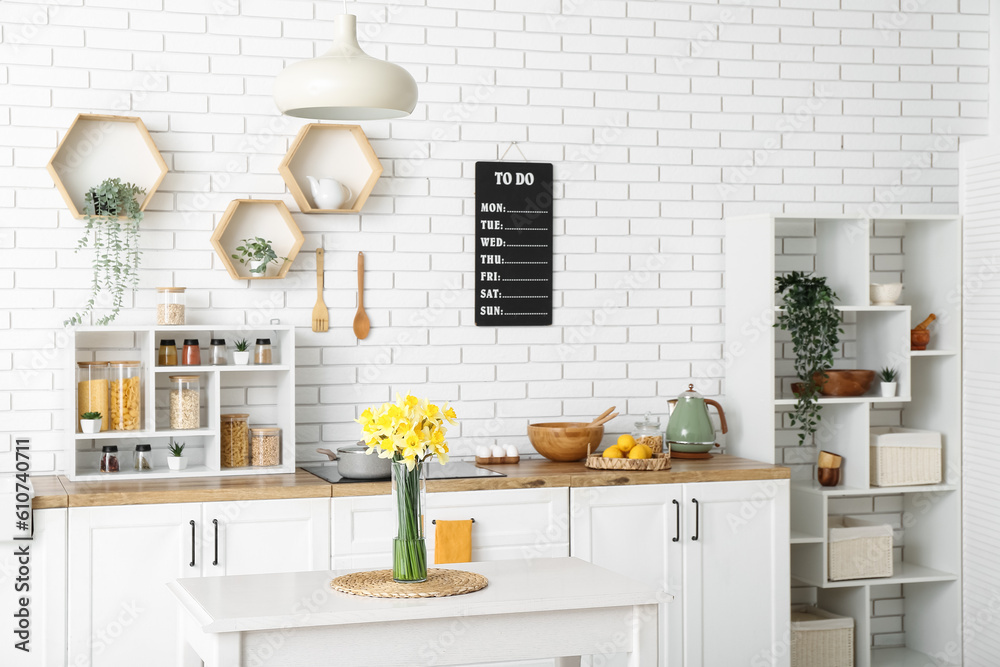 Vase with blooming narcissus flowers on table in interior of kitchen