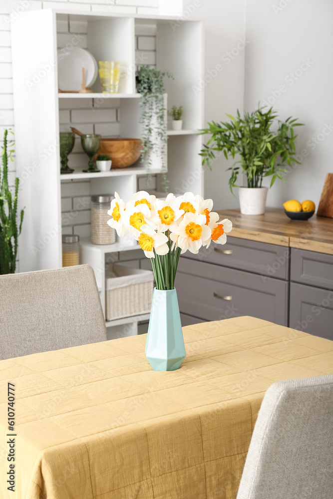 Interior of modern kitchen with blooming narcissus flowers in vase on table