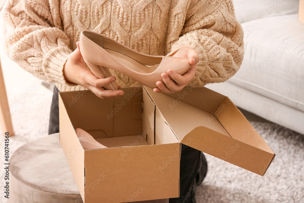 Woman taking out beige leather heels from box in room