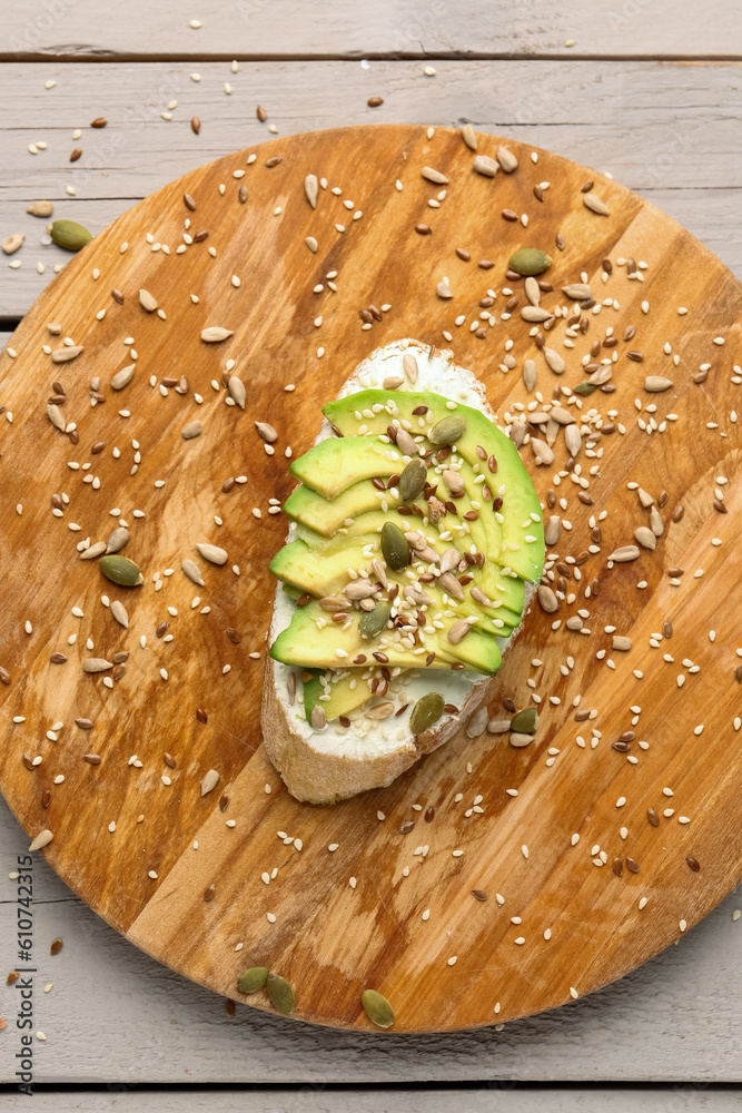 Board of tasty bruschetta with avocado on light wooden background