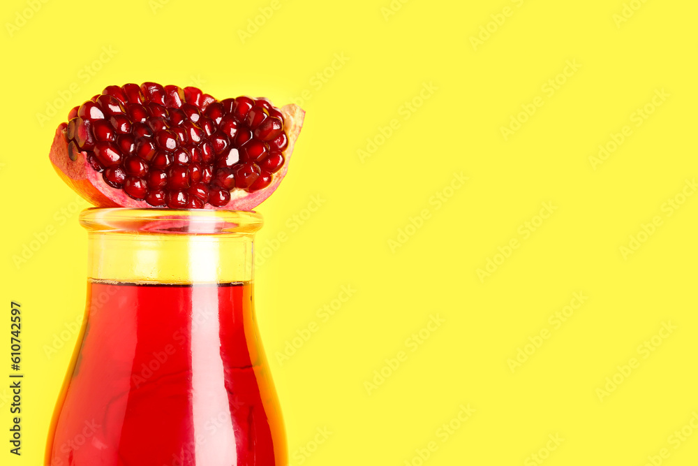 Bottle of fresh pomegranate juice on yellow background