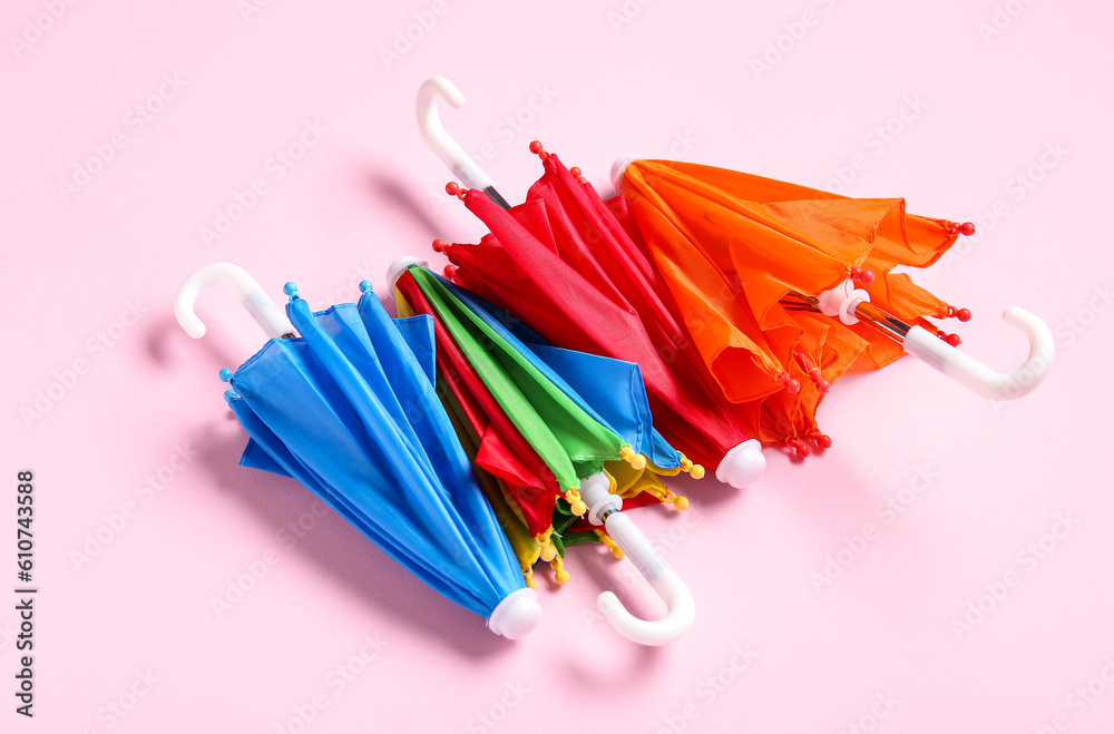 Different mini umbrellas on pink background