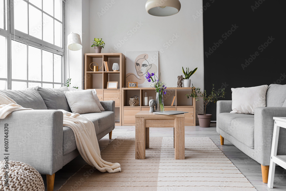 Interior of light living room with grey sofas and big window