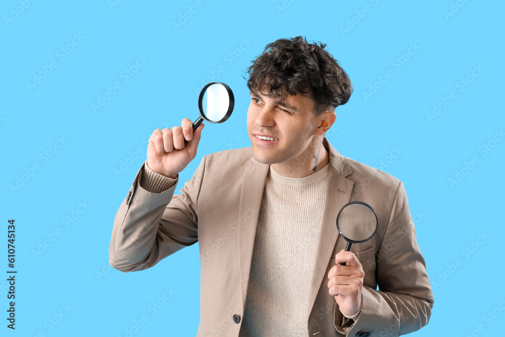 Young man with magnifiers on blue background