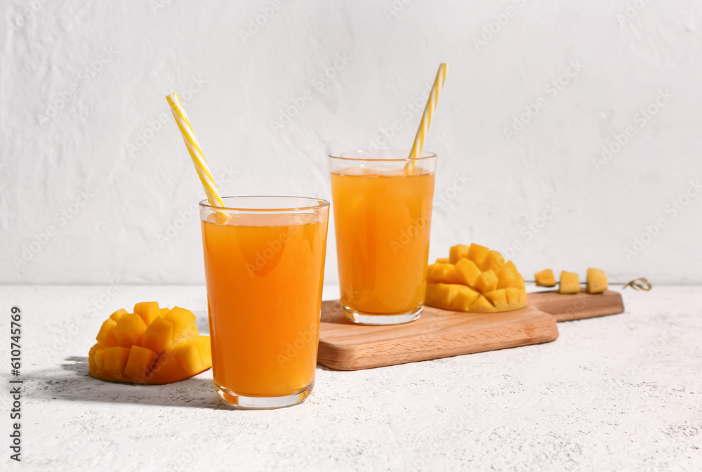 Glasses of fresh mango smoothie on light background