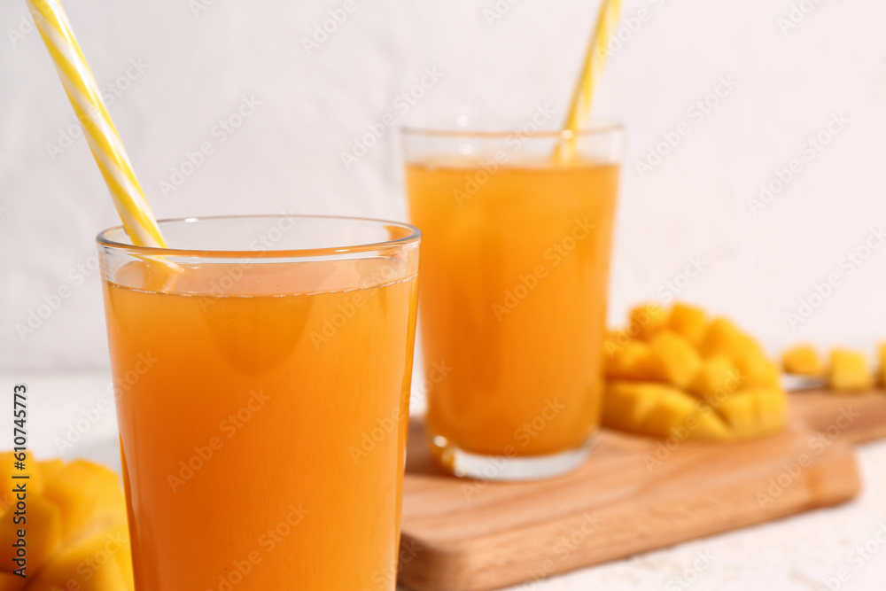 Glasses of fresh mango smoothie on light background, closeup