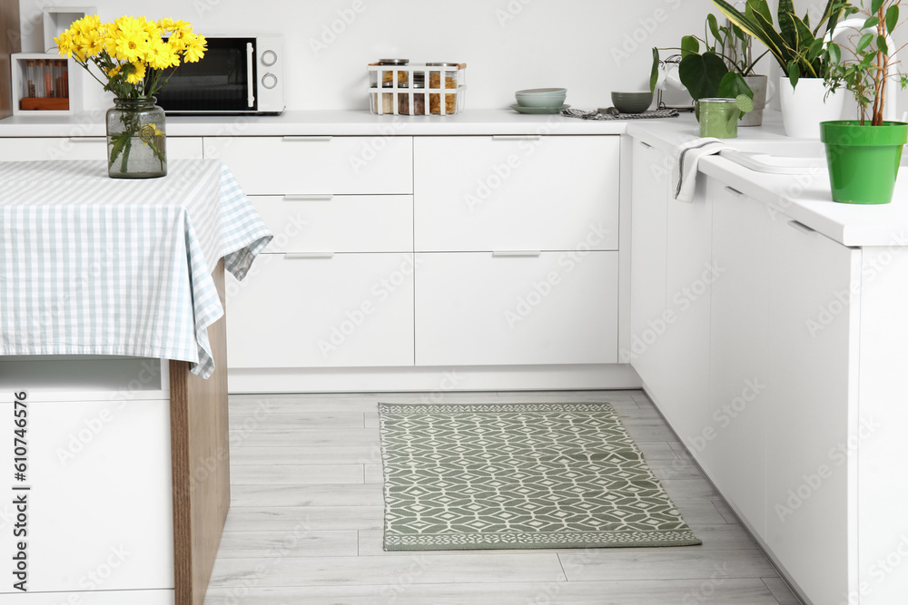 Interior of light kitchen with white counters and rug