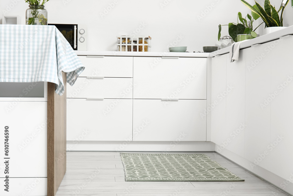 Stylish rug on floor in light kitchen